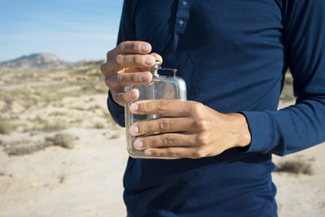 Close up view on man graceful hands opening metal flask with clean fresh water in desert.