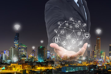 Smart businessman holding digital network in Smart city, Everything icon and wireless communication network, digital connecting world visual, internet of things (IoT) and Digital era. Marketing 4.0