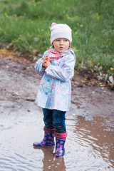 Little girl staying in the puddle and looking at the right