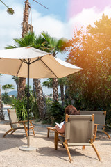 A girl on vacation, under an umbrella and palm trees