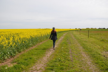 Mädchen von hinten auf dem Weg durch Felder