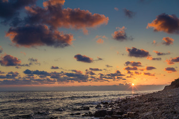 Beautiful sunset among the unimaginable clouds with glimpses of rays on the sea