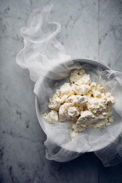 Homemade soft cheese with cheesecloth, overhead view