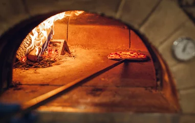Schilderijen op glas Italian pizza is cooked in a wood-fired oven. © andrew_shots