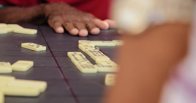 Senior Hispanic Man Playing Domino With Old Friends