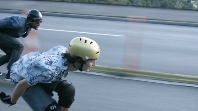 Skateboarders speeding down highway tracking shot. 