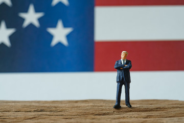 miniature people, happy american businessman standing on wood floor in front of United State national flag in the background as celebrating the Independence day