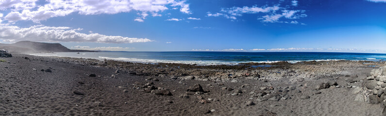 Seaside beach dark sand blue sky