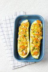 Zucchini boats in a blue baking dish on stone background. 