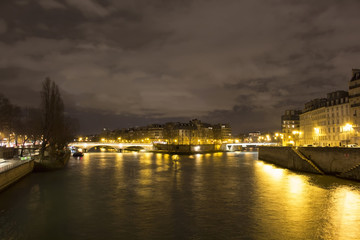 View of long exposed Seine river and historical architecture buildings in Paris at night in winter.