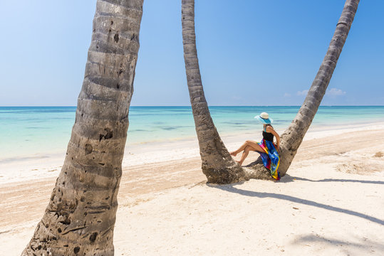 Juanillo Beach (playa Juanillo), Punta Cana, Dominican Republic. Woman under high palm trees on the beach (MR)