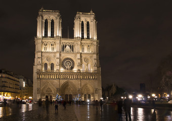 People are in blurry motion around Notre Dame cathedral at night