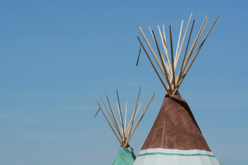 Tops of two teepees against blue sky © merrimonc