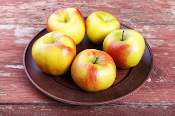 ripe in a dish apples on a wooden table, summer harvest, healthy eating.