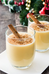 Homemade eggnog with cinnamon on wooden table. Typical Christmas dessert.
