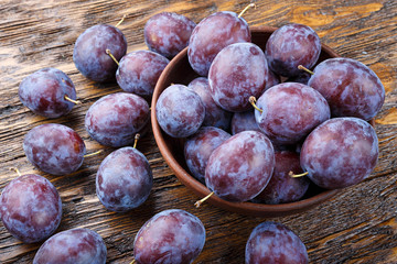 Plums in a clay plate rustic background