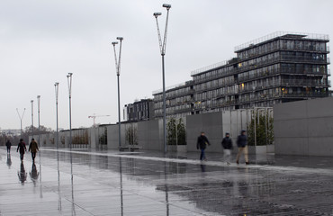 People walk in blurry motion. Modern building is in the background. It's a rainy day in Paris.