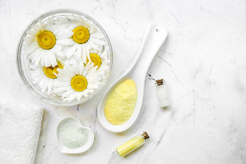 natural cosmetics with bowl of chamomiles for manicure on white textural background top view space for text
