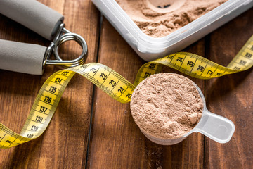 sport diet nutrition and fitness equipment , bars and measure tape wooden background