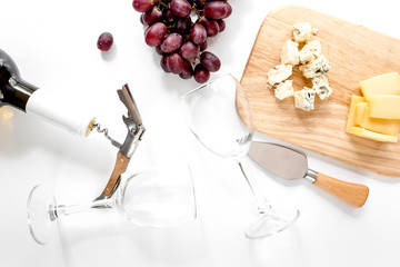 Fototapeta na wymiar Bottle of red wine and wine glasses with cheese and grape aperitive on white background top view