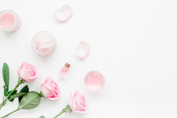 cosmetic set with rose blossom and body cream on white desk background top view mock-up