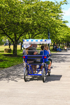 Visitors riding a quad-bicycle along the Governor Tom McCall Waterfront Park in Portland OR, USA