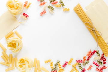 Assortment of different shape italian pastas on white background top view copyspace