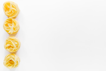 Italian pasta fettuccine nest on white background top view copyspace