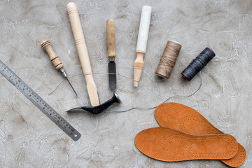 Fototapeta na wymiar Set of cobbler tools on grey stone desk background top view