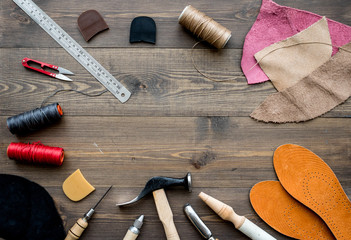 Set of cobbler tools on brown wooden desk background top view copyspace
