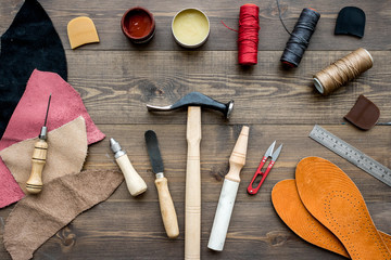 Fototapeta na wymiar Set of cobbler tools on brown wooden desk background top view