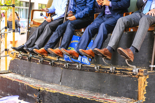 Close-up of men sitting having their shoes cleaned at a shoeshine stand in San Francisco CA, USA