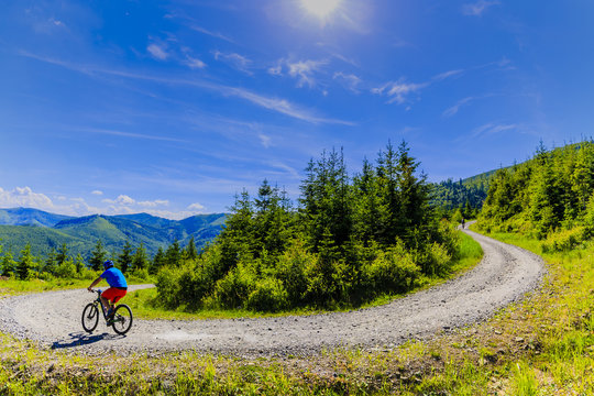 Mountain biker riding on bike in summer mountains forest landscape. Man cycling MTB flow trail track. Outdoor sport activity.