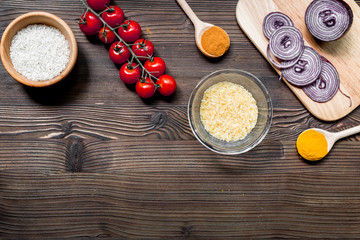 paella home cooking with rice, tomato, onion and spices for ingredients on wooden background top view space for text