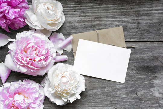 blank greeting card or wedding invitation and envelope with tender peonies flowers