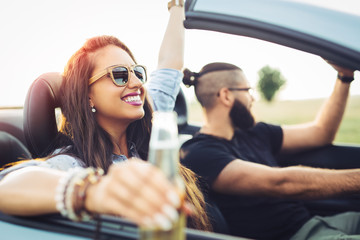 Freedom of the open road.Young Couple Driving Along Country Road In Open Top Car.