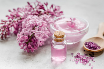 Fototapeta na wymiar take bath with lilac cosmetic set and blossom on stone table background