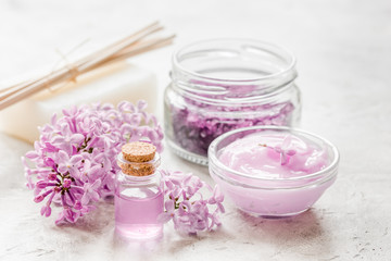 Obraz na płótnie Canvas spa cosmetic set with lilac flowers stone desk background