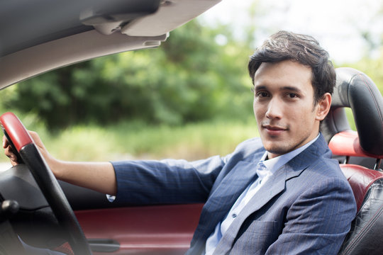 Handsome Man Driving Supercar At Outdoor Place And Looking Camera.