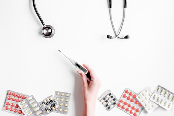 Medical equipment with stethoscope and pills in doctor's office on white desk background top view