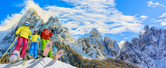 Skiing family enjoying winter vacation on snow in sunny cold day in mountains and fun. San Martino di Castrozza, Italy.
