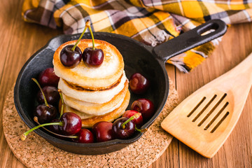 A pile of home fried pancakes and berries cherries in a pan