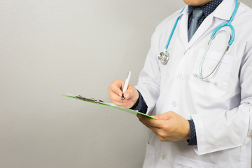 Male Doctor with files and stethoscope on hospital corridor holding clipboard and writing a prescription,Doctors Medical Exam,Healthcare and medical concept,test results, registration,selective focus.