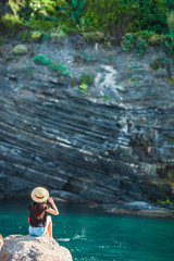 Young girl in a cove on a rock in the Cinque Terre Reserve. Stunning nature and fresh air