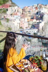 Beautiful woman on breakfast at outdoor cafe with amazing view in Cinque Terre