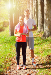 Young couple stretching legs before running in autumn nature