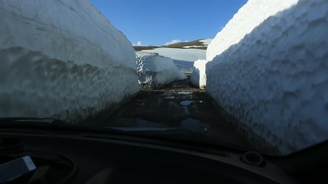 Travel by car on broken roads from Batumi to Borjomi. Road trip through walls of old snow. Akhaltsikhe region, Georgia.