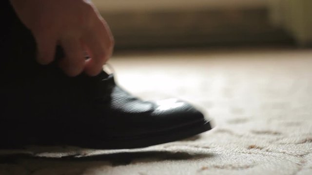 The man laces and tie his shoelaces on black shoes
