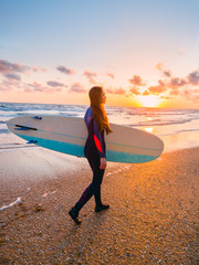 Fototapeta na wymiar Surf girl with surfboard on beach and ocean, warm sunset colors