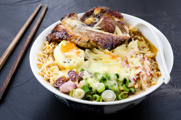 Japanese ramen noodle soup with pork, egg, onion and cheese on dark wooden background